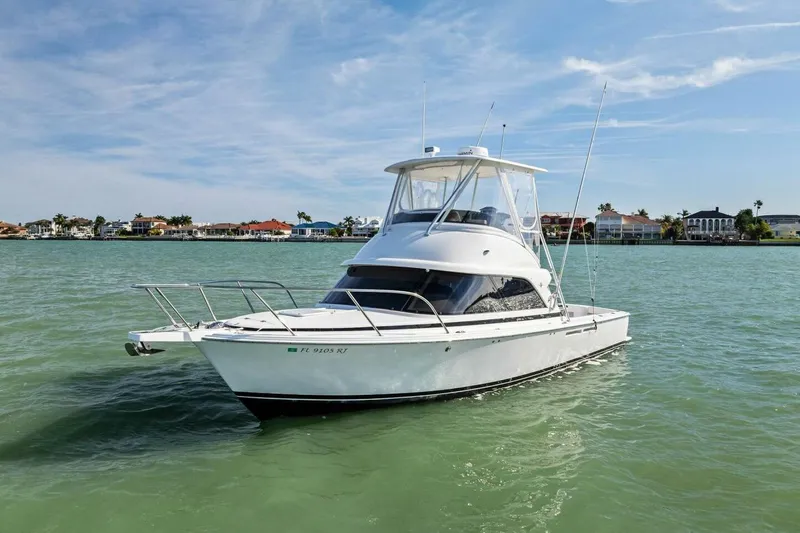 Still Dancing Yacht Photos Pics 2017 Bertram 35 Flybridge boat on calm water, with coastal homes in the background.