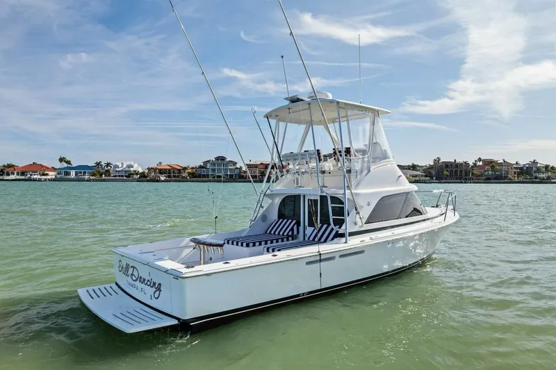 Still Dancing Yacht Photos Pics 2017 Bertram 35 Flybridge yacht on calm waters, with coastal homes in the background.