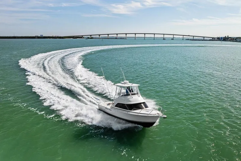 Still Dancing Yacht Photos Pics 2017 Bertram 35 Flybridge cruising on open water with bridge in background.