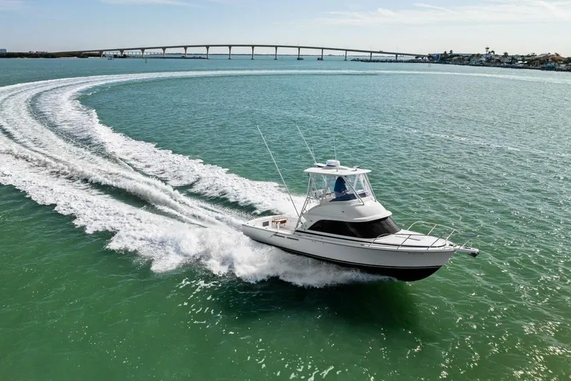 Still Dancing Yacht Photos Pics 2017 Bertram 35 Flybridge cruising on turquoise waters near a bridge.