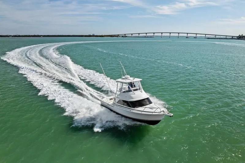 Still Dancing Yacht Photos Pics 2017 Bertram 35 Flybridge cruising on turquoise waters near a bridge.