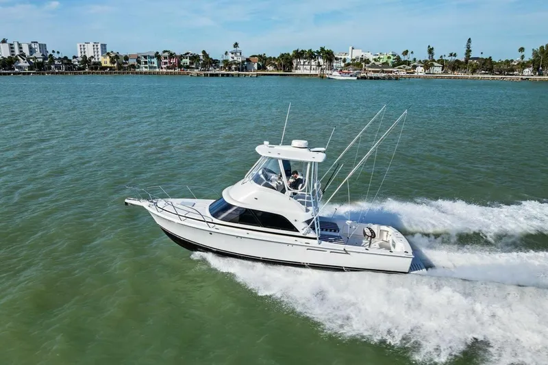 Still Dancing Yacht Photos Pics 2017 Bertram 35 Flybridge cruising on open water near coastal cityscape.