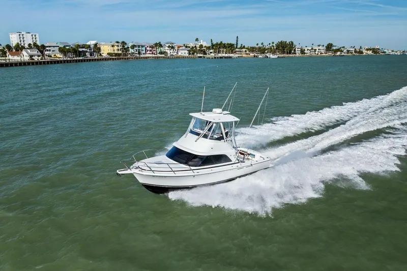Still Dancing Yacht Photos Pics 2017 Bertram 35 Flybridge cruising on open water near a coastal town.