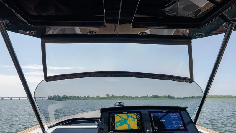  Yacht Photos Pics 2023 Pardo Yachts P38 cockpit view with navigation screens on a calm waterway.