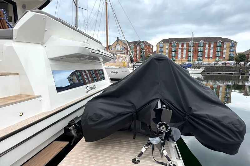 Serenity Yacht Photos Pics 2023 Prestige 460S yacht docked with covered equipment, reflecting waterfront buildings.