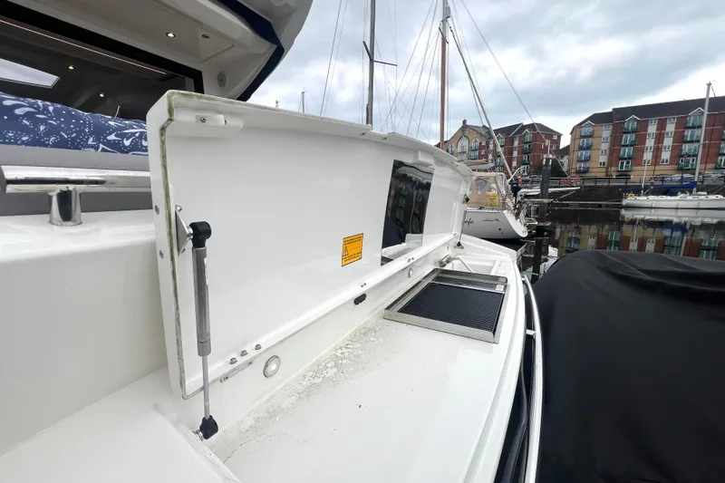 Serenity Yacht Photos Pics 2023 Prestige 460S yacht deck with open storage compartment, docked in marina.