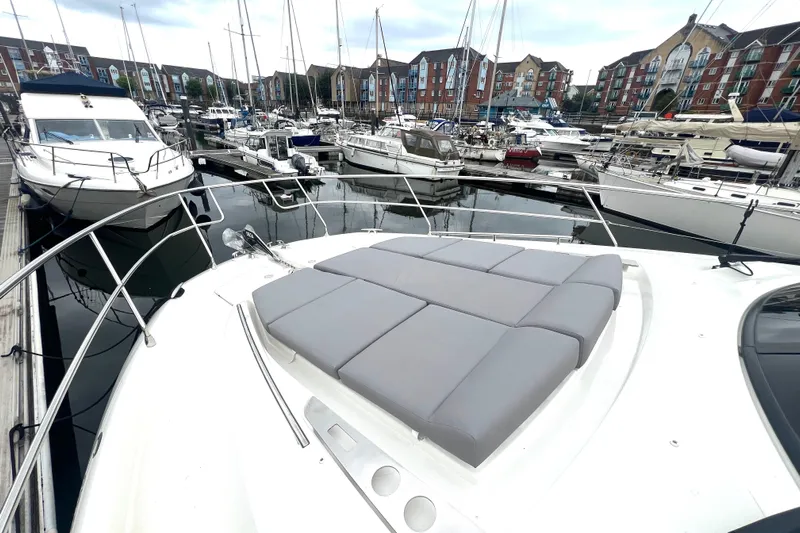 Serenity Yacht Photos Pics 2023 Prestige 460S yacht with sunbathing area, docked in a marina with other boats.