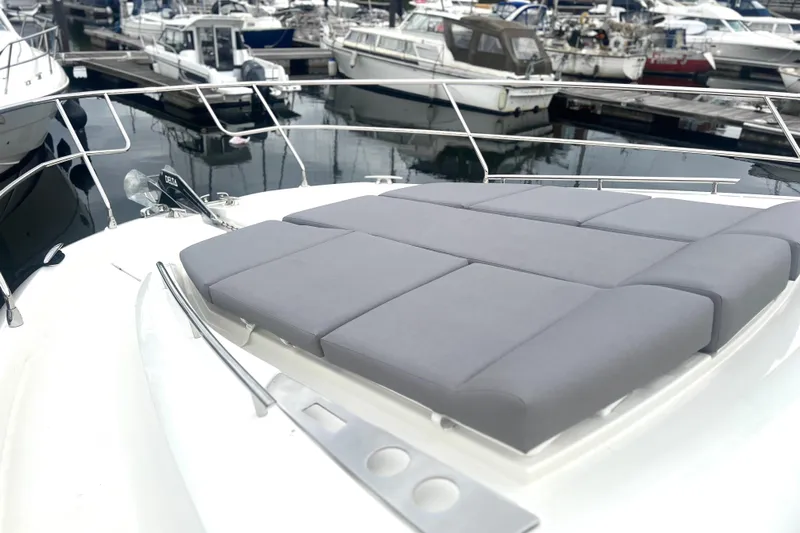 Serenity Yacht Photos Pics 2023 Prestige 460S yacht with cushioned sunbathing area, docked at marina.