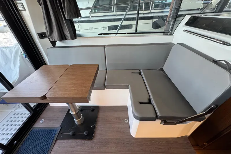  Yacht Photos Pics Interior of 2025 Beneteau Antares 11 Fly with gray seating and wooden table.