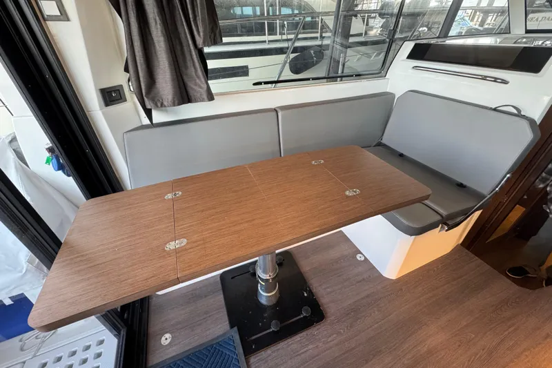  Yacht Photos Pics Interior of 2025 Beneteau Antares 11 Fly with wooden table and gray seating.