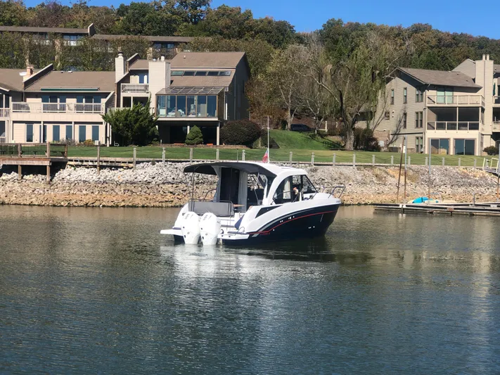  Yacht Photos Pics 2022 Beneteau Antares 9 boat on calm water near waterfront homes.
