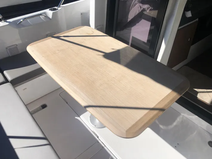  Yacht Photos Pics Wooden table on 2022 Beneteau Antares 9 boat, featuring sleek interior design.