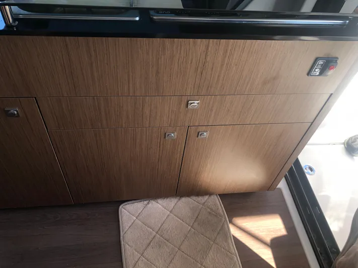  Yacht Photos Pics Interior of 2022 Beneteau Antares 9, featuring wooden cabinetry and a beige mat.