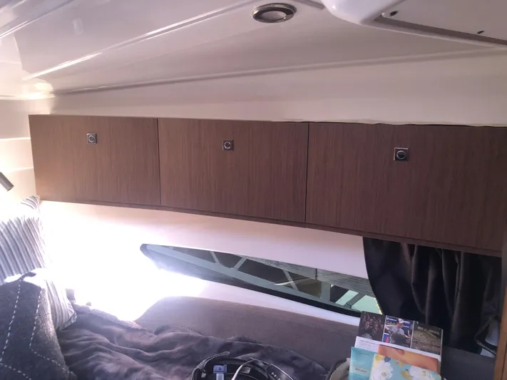  Yacht Photos Pics Interior cabin of 2022 Beneteau Antares 9 with wooden cabinets and cozy bedding.