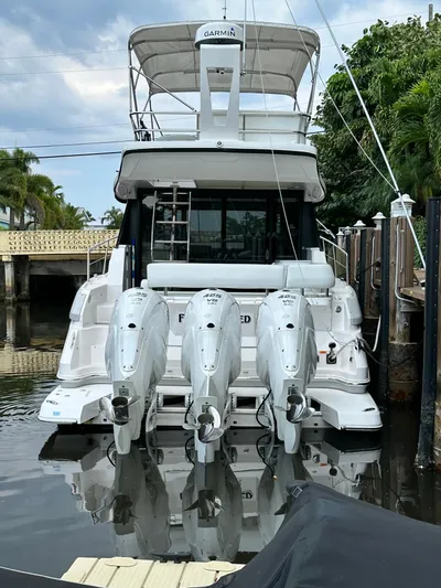 Fully Vested Yacht Photos Pics 2022 Regal 42 FXO yacht with triple outboard engines docked in a marina.