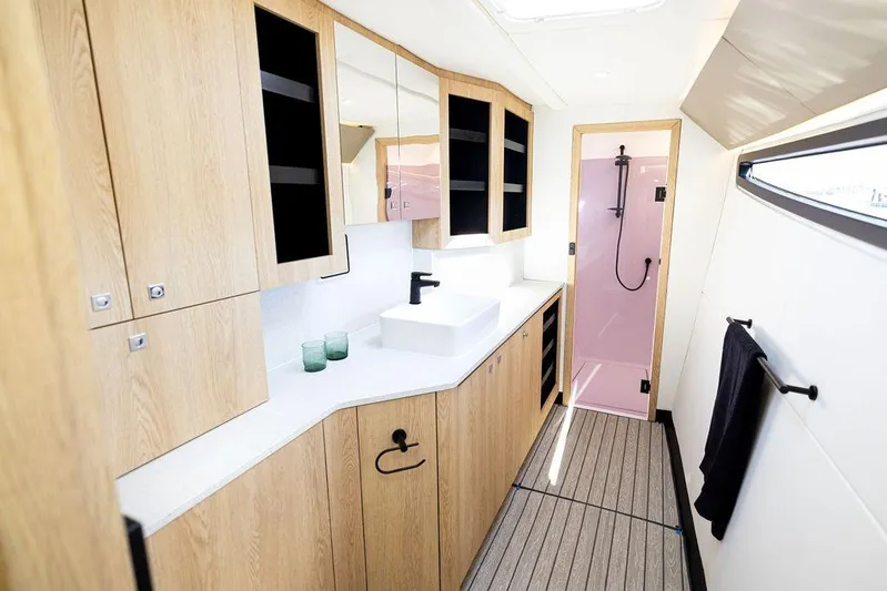  Yacht Photos Pics Modern yacht bathroom with wooden cabinets, sleek sink, and pink shower in Introductory Cure Marine 55, 2025.