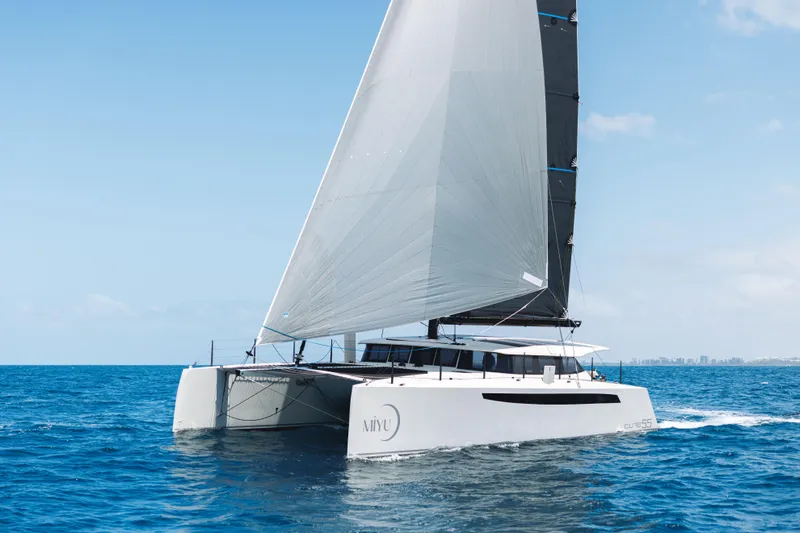  Yacht Photos Pics 2025 Introductory Cure Marine 55 catamaran sailing on open sea under clear blue sky.