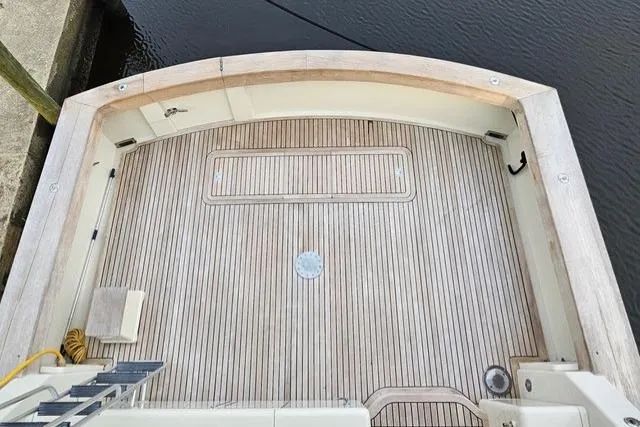 Andiamo Yacht Photos Pics 1991 Donzi 65 Sportfisher boat deck with wooden flooring, docked by the water.