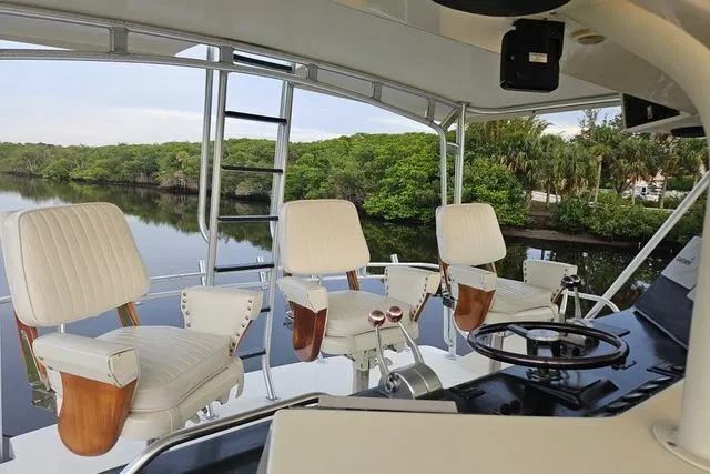 Andiamo Yacht Photos Pics 1991 Donzi 65 Sportfisher helm with three white captain chairs overlooking serene waterway.