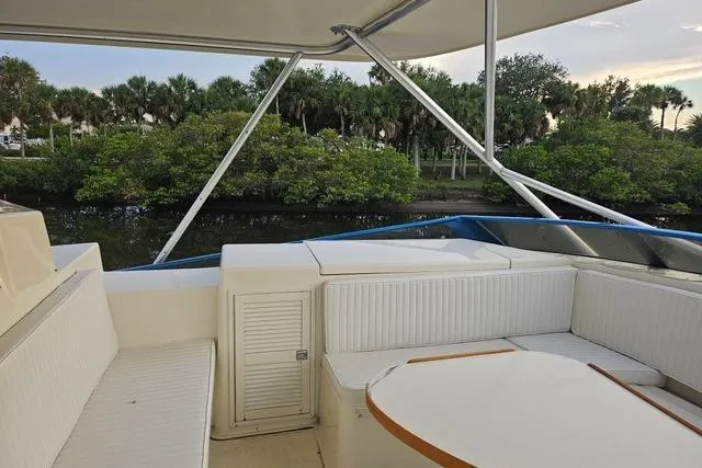 Andiamo Yacht Photos Pics 1991 Donzi 65 Sportfisher yacht interior with white seating, table, and lush greenery view.