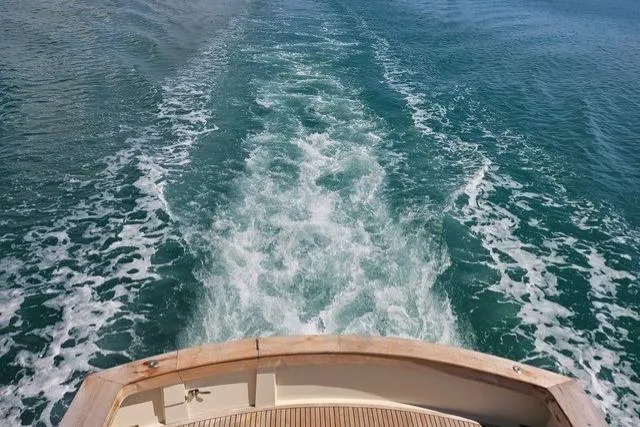 Andiamo Yacht Photos Pics 1991 Donzi 65 Sportfisher cruising, leaving a wake in clear blue water.