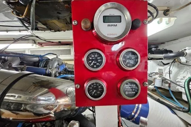 Andiamo Yacht Photos Pics Engine room of 1991 Donzi 65 Sportfisher with red gauge panel and RPM meter.