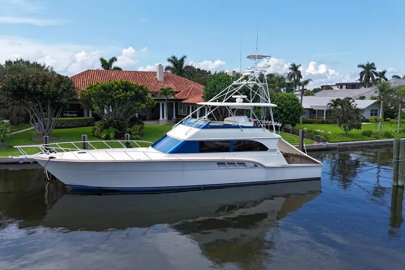 Andiamo Yacht Photos Pics 1991 Donzi 65 Sportfisher yacht docked by waterfront homes, reflecting on calm water.