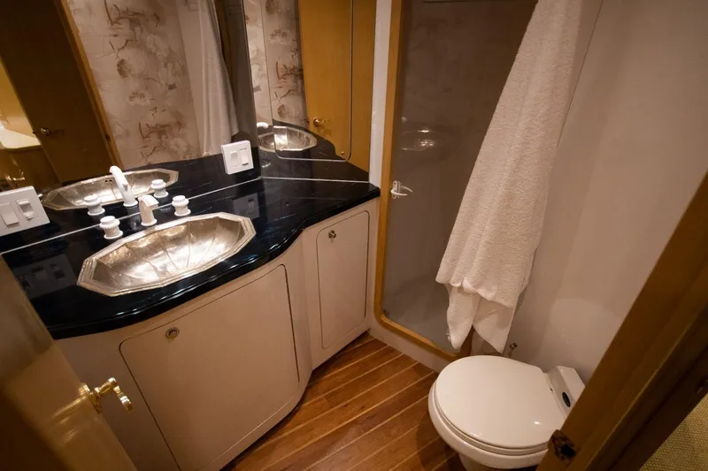 Andiamo Yacht Photos Pics Luxurious bathroom in 1991 Donzi 65 Sportfisher yacht with elegant fixtures and wood flooring.