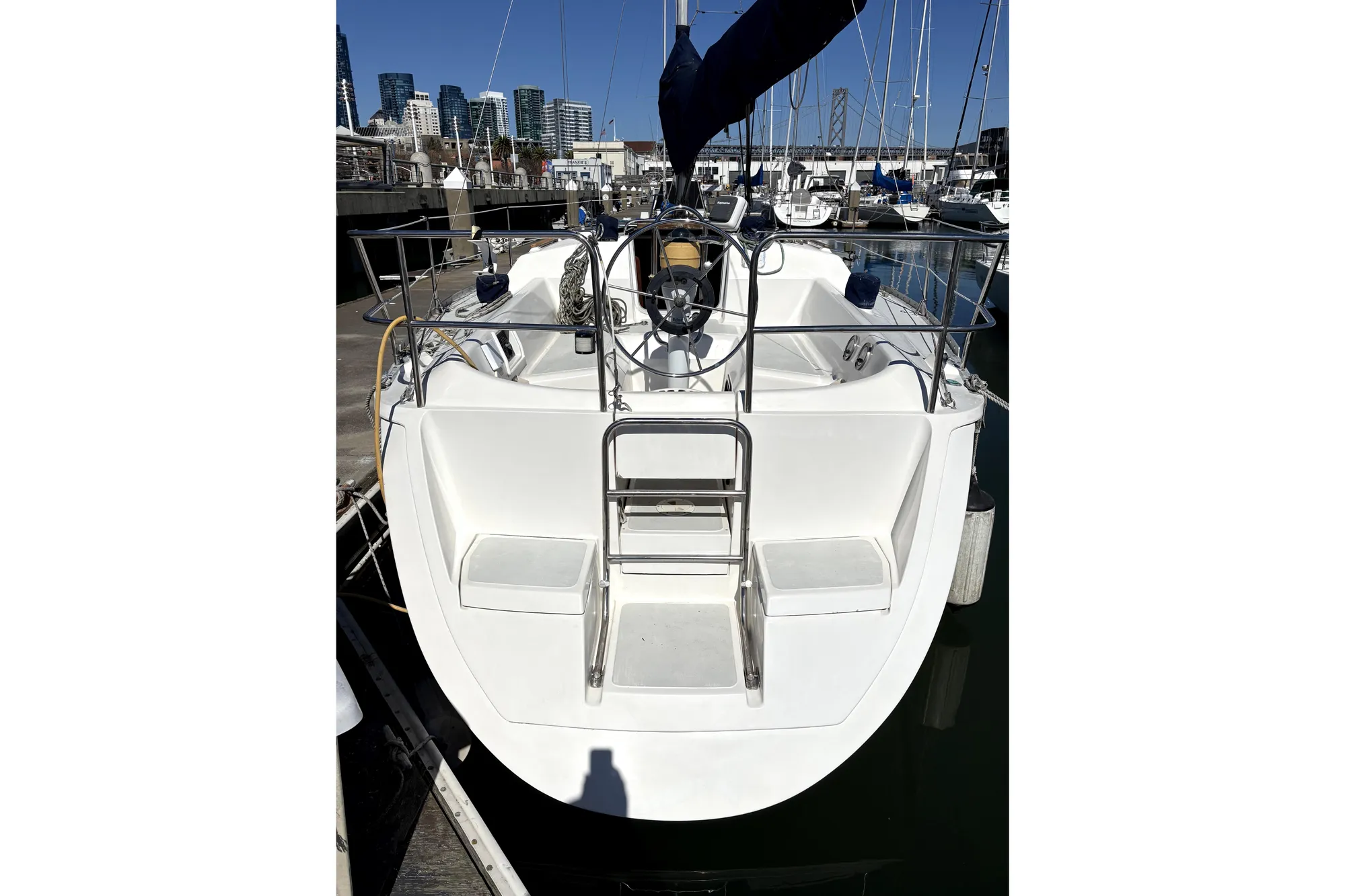 1989 Hunter 30 sailboat docked at marina, featuring a clean white deck and stainless steel ladder.