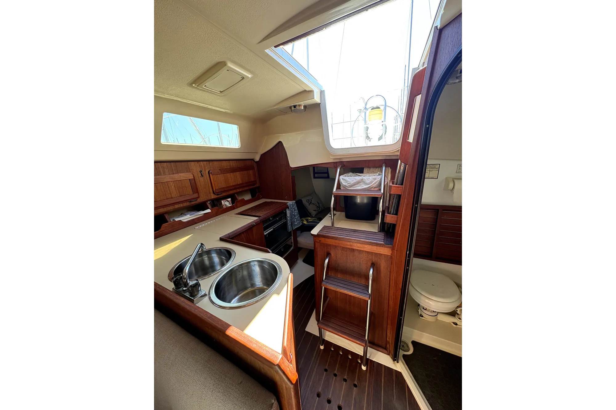 Interior of 1989 Hunter 30 sailboat with compact kitchen and wooden cabinetry.