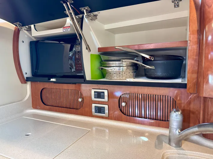 Tranquilo Yacht Photos Pics 2004 Sea Ray 360 Sundancer kitchen with microwave, cookware, and wooden cabinets.