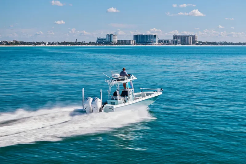  Yacht Photos Pics 2023 Barker Boatworks 26 Open cruising on clear blue ocean near city skyline.