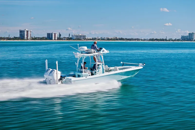  Yacht Photos Pics 2023 Barker Boatworks 26 Open cruising on clear blue water near a coastal city.