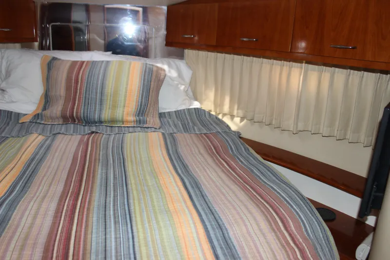  Yacht Photos Pics Cozy bedroom in 2003 Carver 36 Super Sport with striped bedding and wooden cabinets.