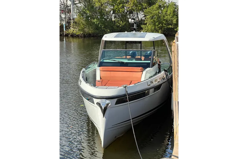 La Flare Yacht Photos Pics 2023 Saxdor 320 GTO boat docked on calm water, featuring sleek design and orange seating.