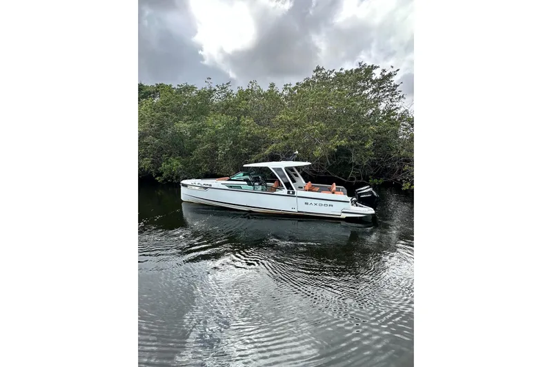 La Flare Yacht Photos Pics 2023 Saxdor 320 GTO boat on calm water near lush greenery.