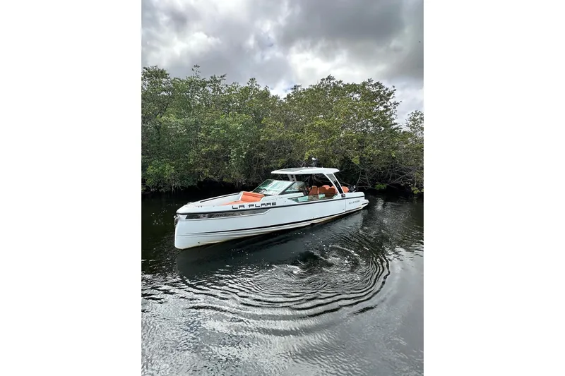 La Flare Yacht Photos Pics 2023 Saxdor 320 GTO boat on calm water, surrounded by lush greenery.