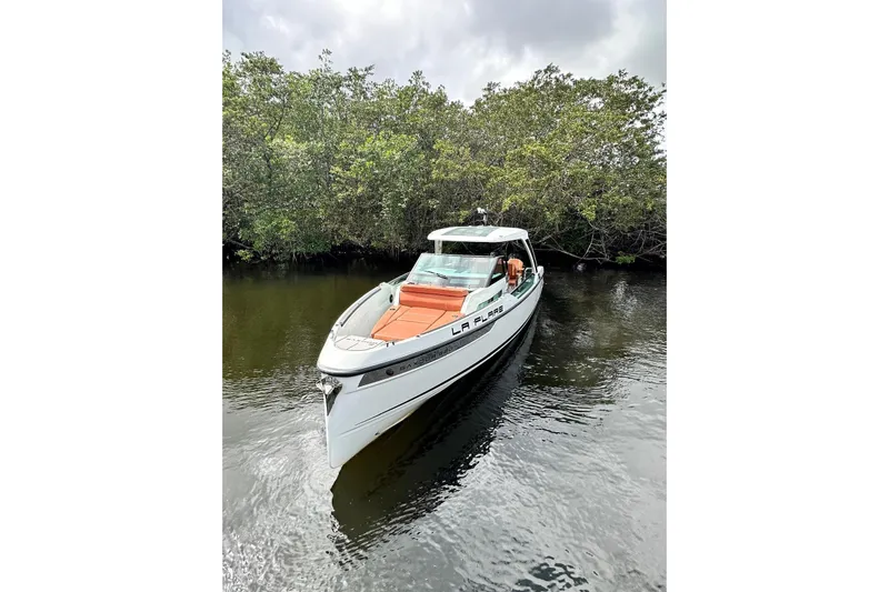 La Flare Yacht Photos Pics 2023 Saxdor 320 GTO boat on calm water, surrounded by lush greenery.