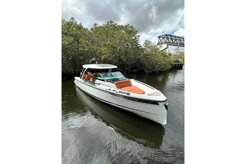 La Flare Yacht Photos Pics 2023 Saxdor 320 GTO boat on calm water, surrounded by lush greenery.