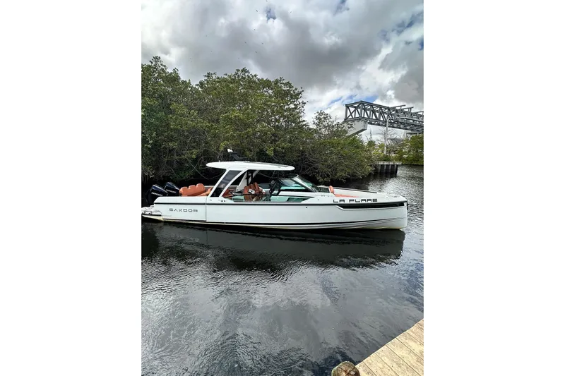 La Flare Yacht Photos Pics 2023 Saxdor 320 GTO boat docked on a calm river under cloudy skies.