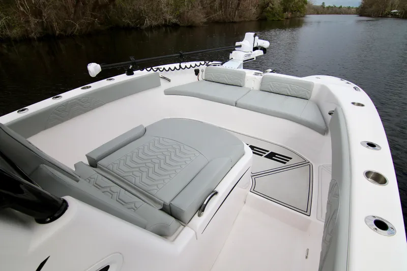 Yacht Photos Pics 2024 Twin Vee 280 GFX CC boat interior with cushioned seating on a calm river.