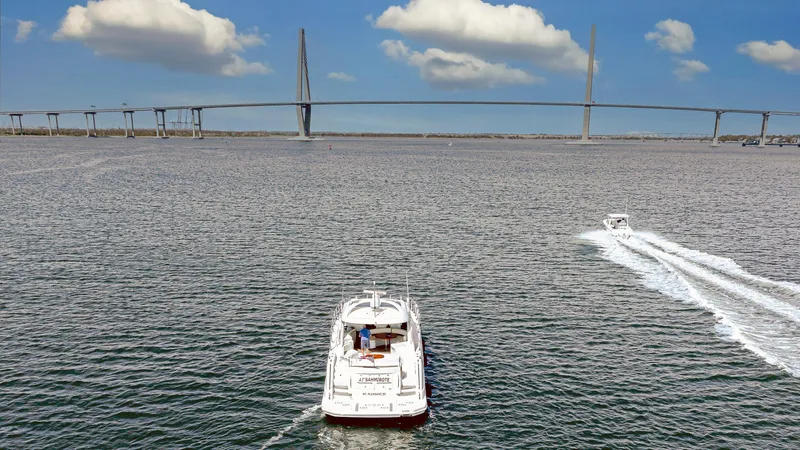 At's Ahmibote V Yacht Photos Pics Sea Ray 580 Sundancer 2011 cruising under a bridge on a sunny day.