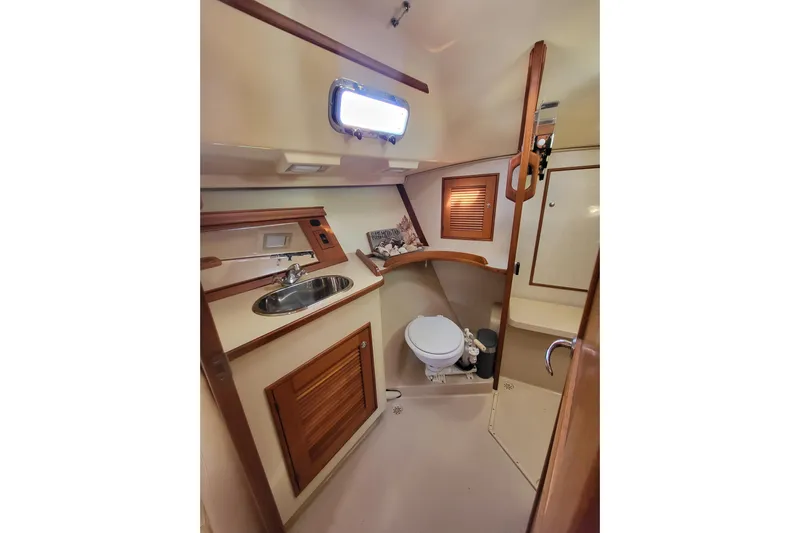 Catharpin Blue Yacht Photos Pics 1984 Island Packet 420 yacht bathroom with sink, toilet, and wooden cabinetry.