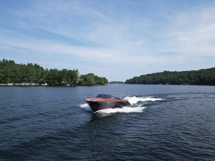  Yacht Photos Pics 2013 Riva Aquariva 33 cruising on a scenic lake under a clear blue sky.