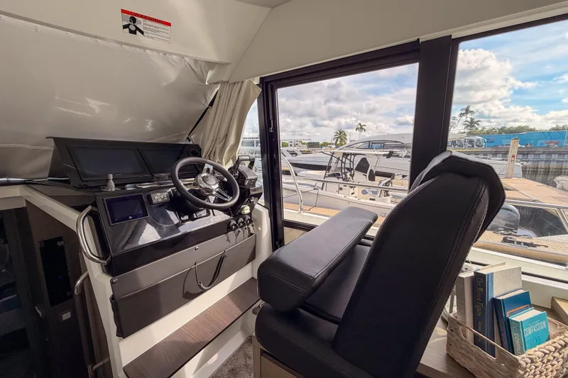 Rhapsody In Sea Yacht Photos Pics Helm of 2025 Jeanneau NC 1295 Fly yacht with modern controls and marina view.