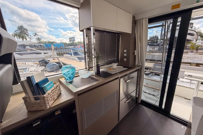 Rhapsody In Sea Yacht Photos Pics Modern kitchen interior of 2025 Jeanneau NC 1295 Fly yacht with outdoor view.