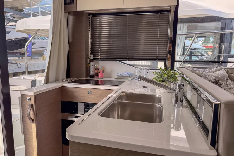 Rhapsody In Sea Yacht Photos Pics Modern kitchen interior of 2025 Jeanneau NC 1295 Fly yacht with sleek countertops and appliances.