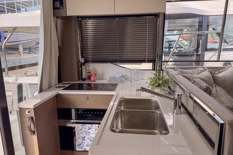 Rhapsody In Sea Yacht Photos Pics Modern kitchen interior on 2025 Jeanneau NC 1295 Fly yacht, featuring sleek countertops and appliances.