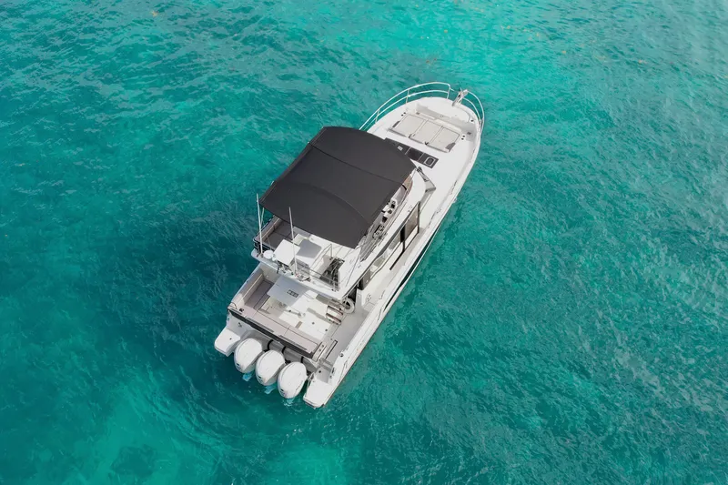 Rhapsody In Sea Yacht Photos Pics 2025 Jeanneau NC 1295 Fly yacht on clear turquoise water, aerial view.