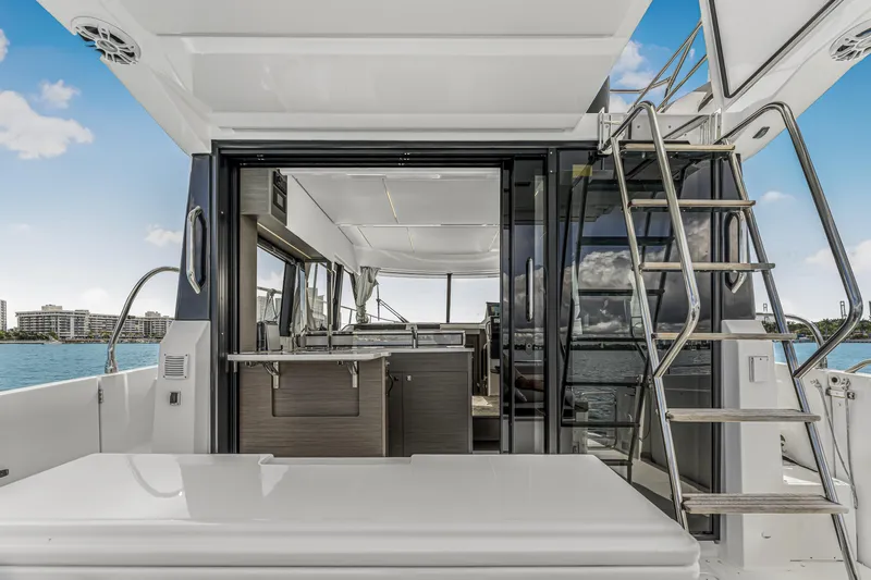 Rhapsody In Sea Yacht Photos Pics 2025 Jeanneau NC 1295 Fly yacht interior with open sliding doors and staircase, ocean view.